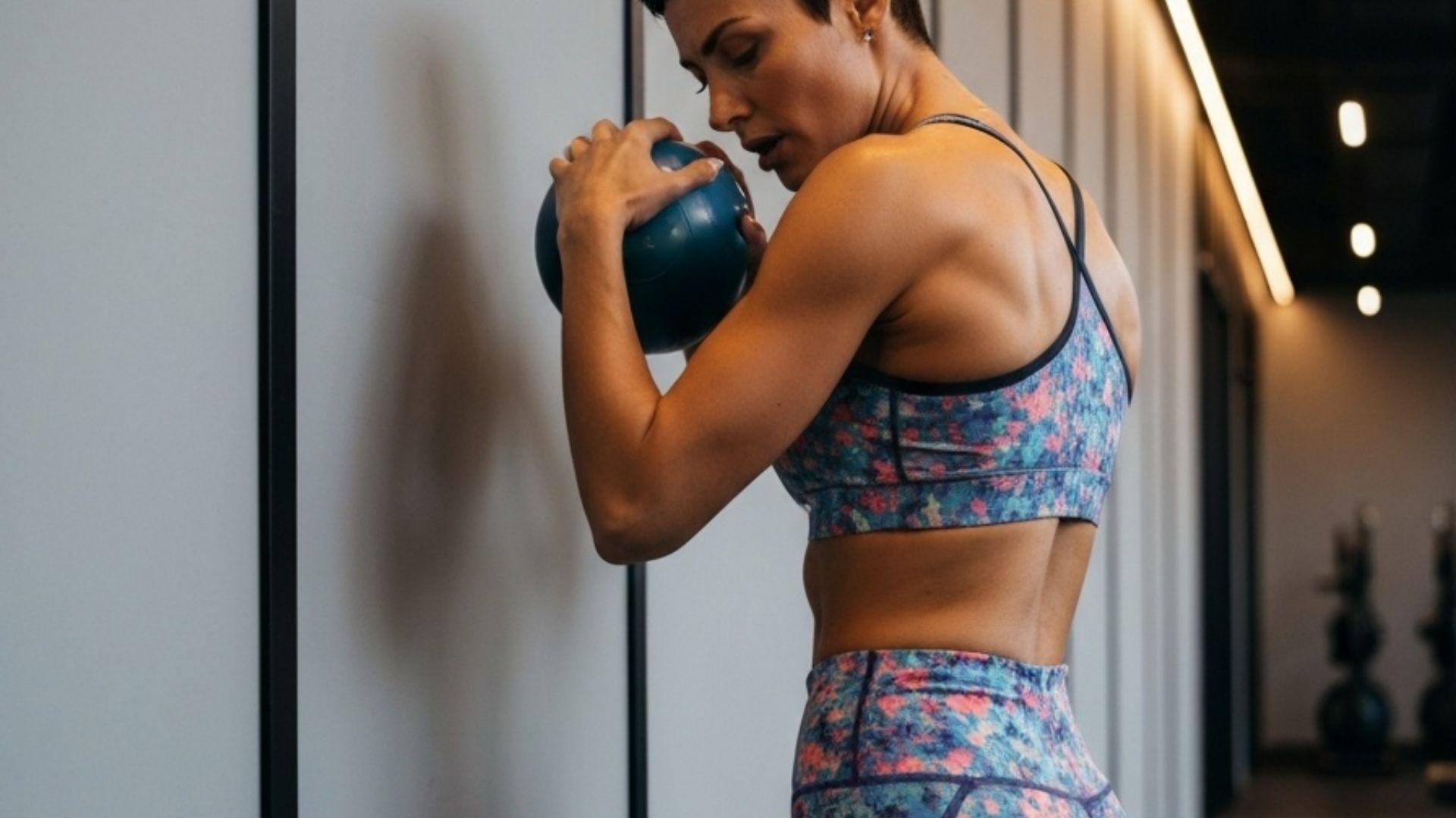 Kvinne bruker massasjeball mot skulderblad for triggerpunktbehandling